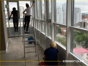 Команда специалистов моет окна на балконе